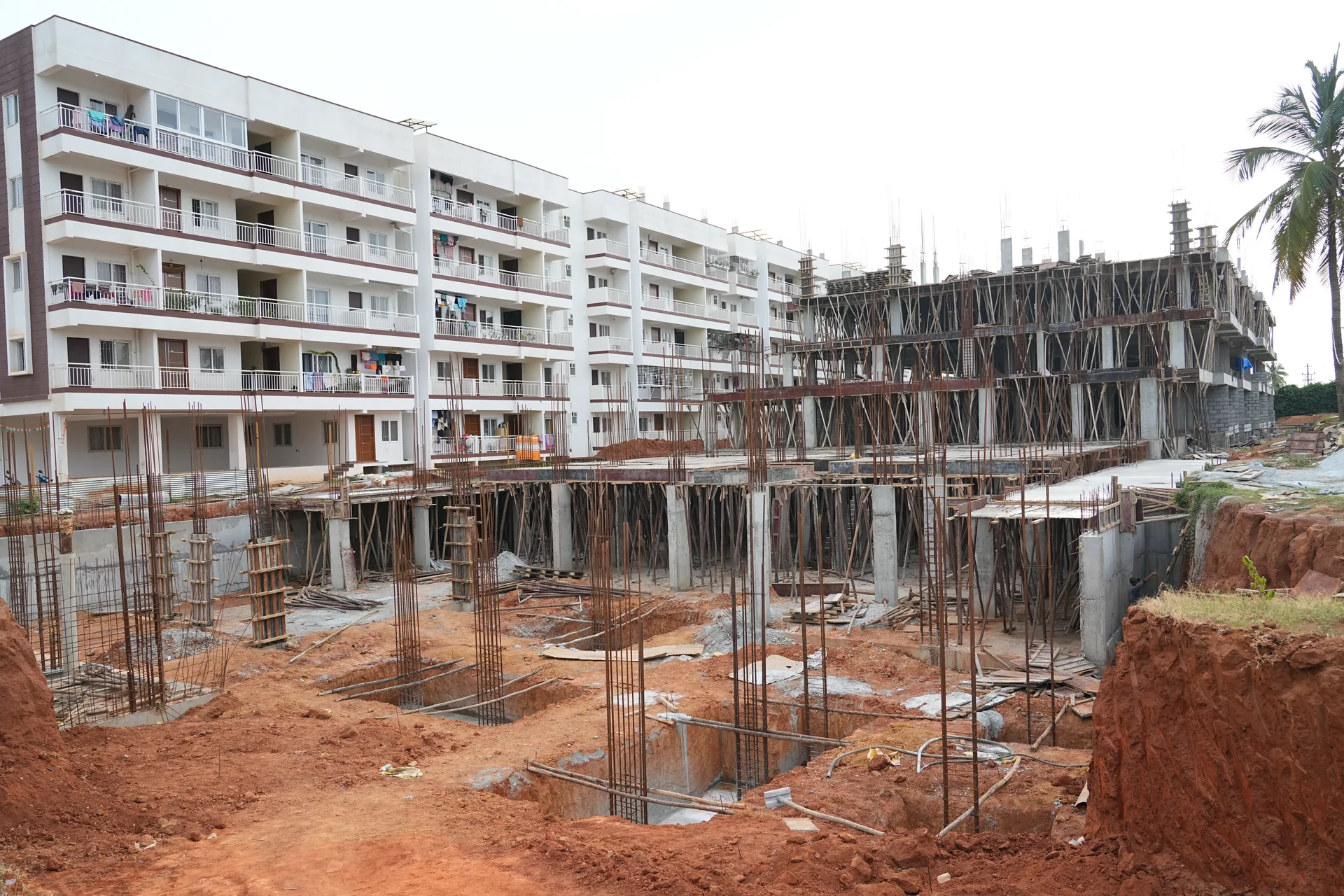 Wide view of the active Sapthagiri Sampada construction site beside the completed residential block